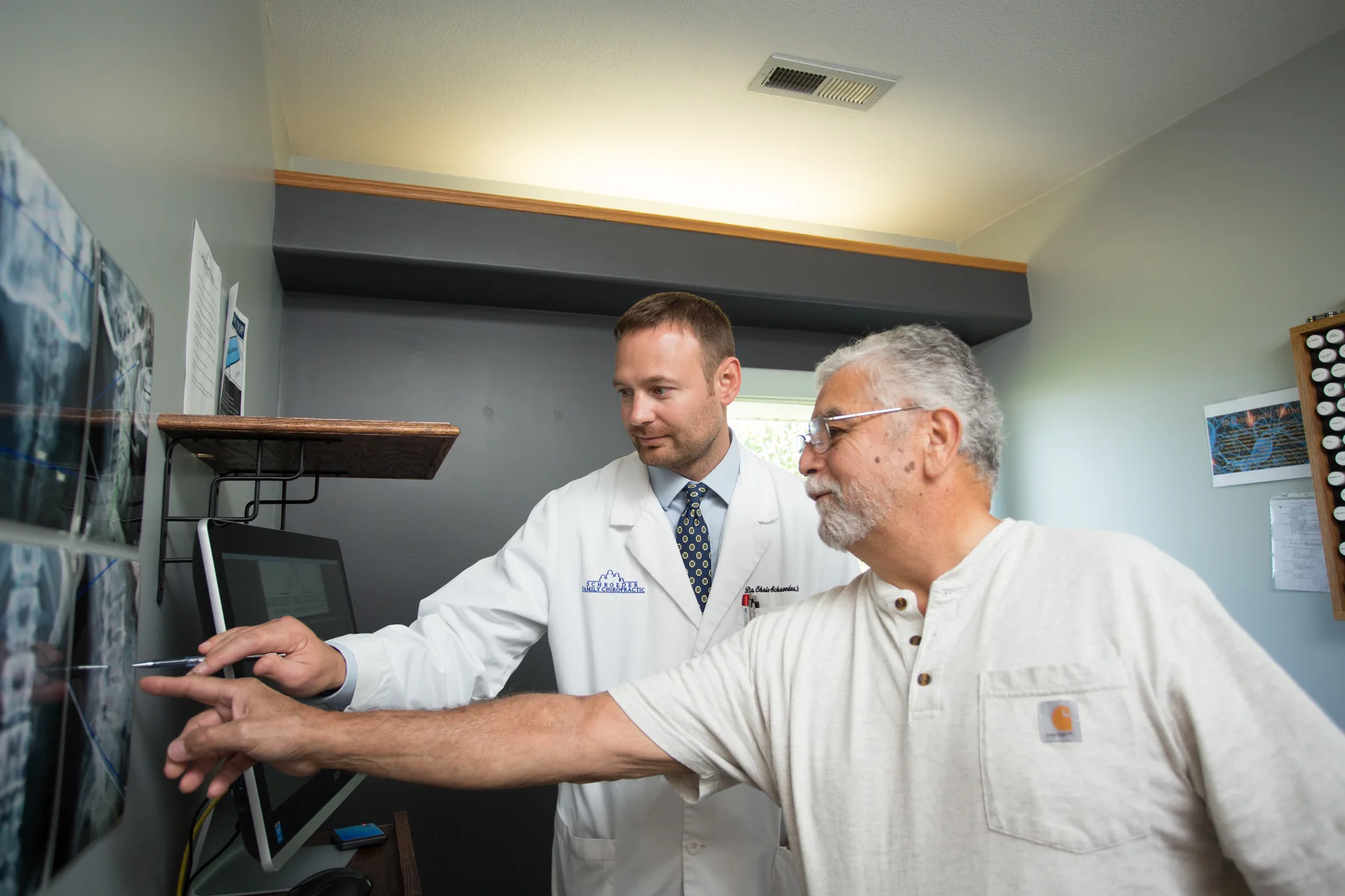 Un profesional clínico y un paciente revisando radiografías de espalda